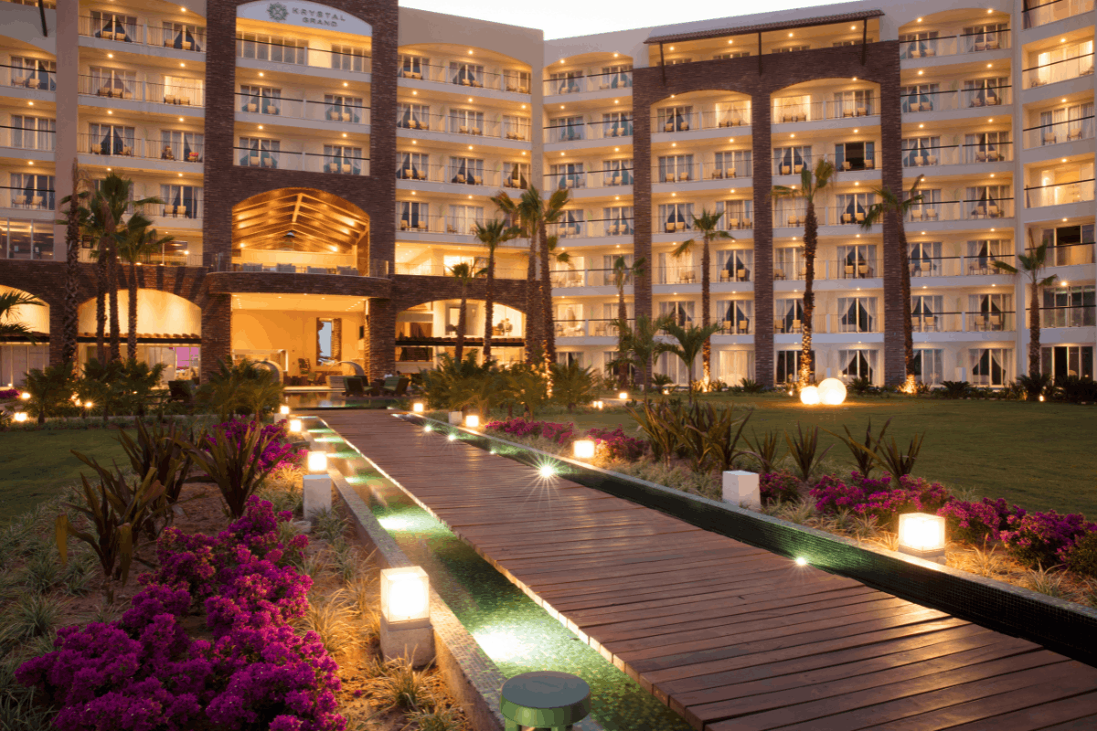 Fachada nocturna de Krystal Grand Los Cabos con jardines iluminados y ambiente elegante.